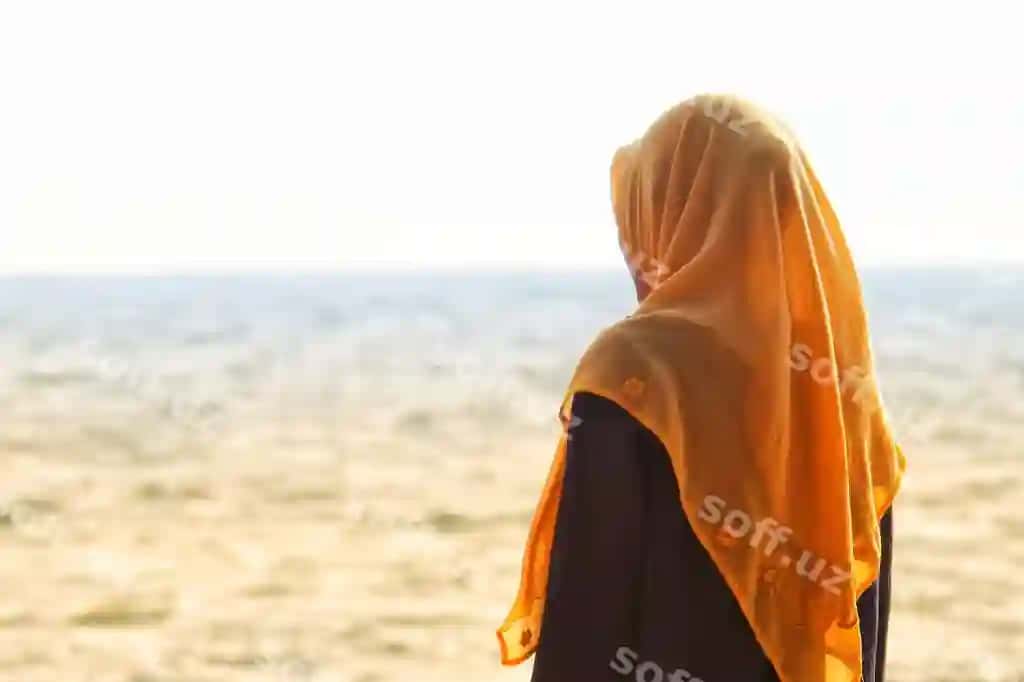 Tomondan ko'rinish o'smir qiz hijab kiygan pochvotda aniq osmon orqali turibdi | Side view teenage girl wearing hijab standing beach against clear sky
