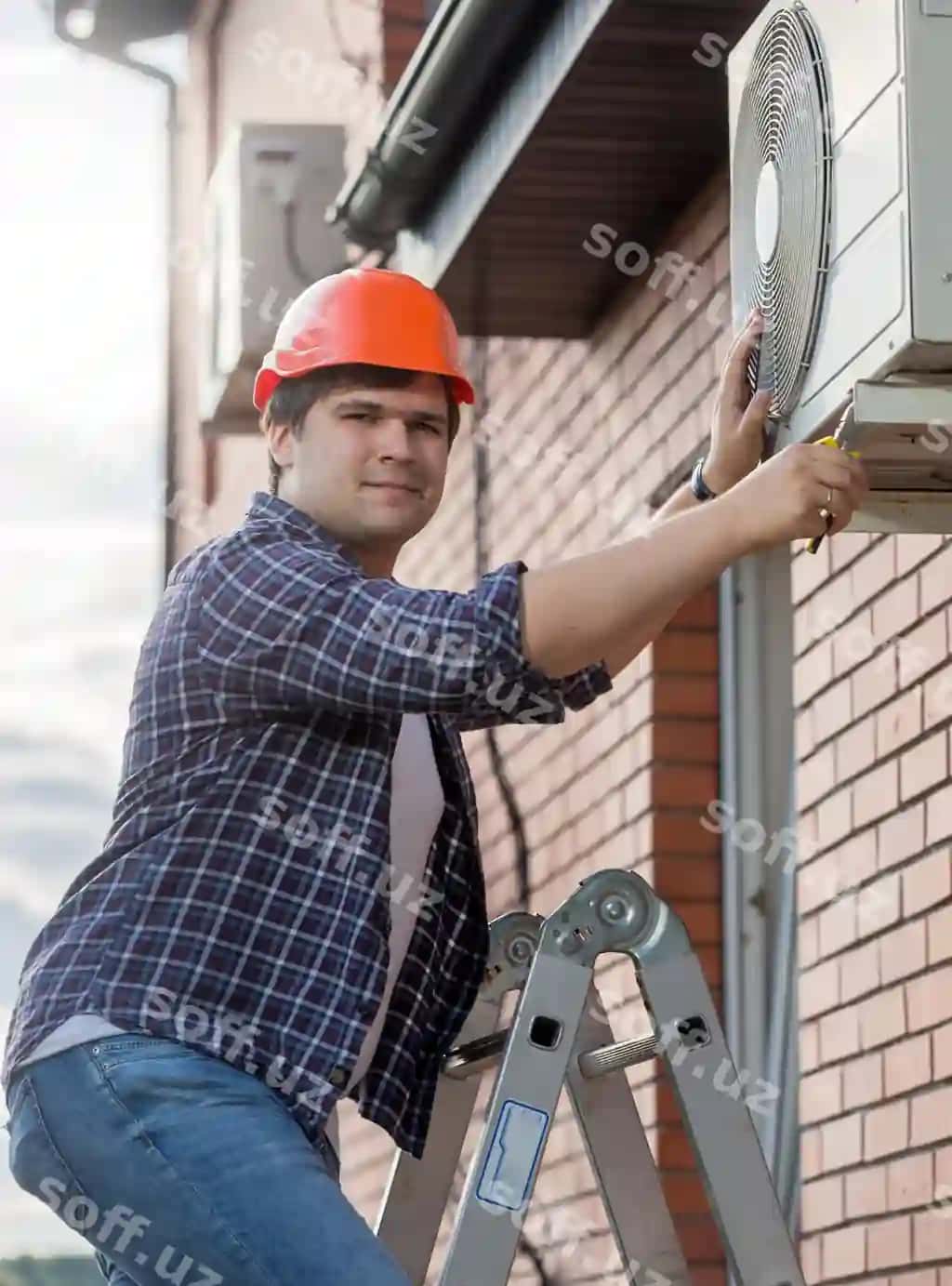 Yosh texnik tashqaridagi konditsionerni ta'mirlayotgan. | Young technician repairing outside air conditioning unit
