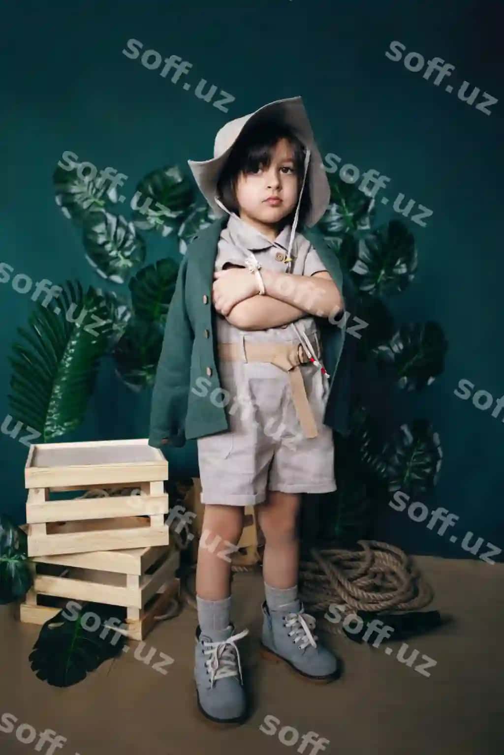 Jiddiy o'g'il bola sayohat qiluvchi shapka o'yinatuvchi yog'ochdan yasalgan kataklar studiya yashil fonda | Serious boy child traveler hat stand wooden boxes studio green background