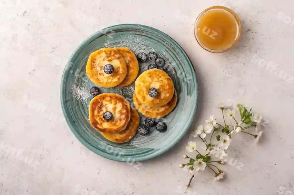 Traditsional rus cheesecake kokaroch va shirin keramika likop yorqin fonda | Traditional russian cheesecake with blueberries honey ceramic plate light background
