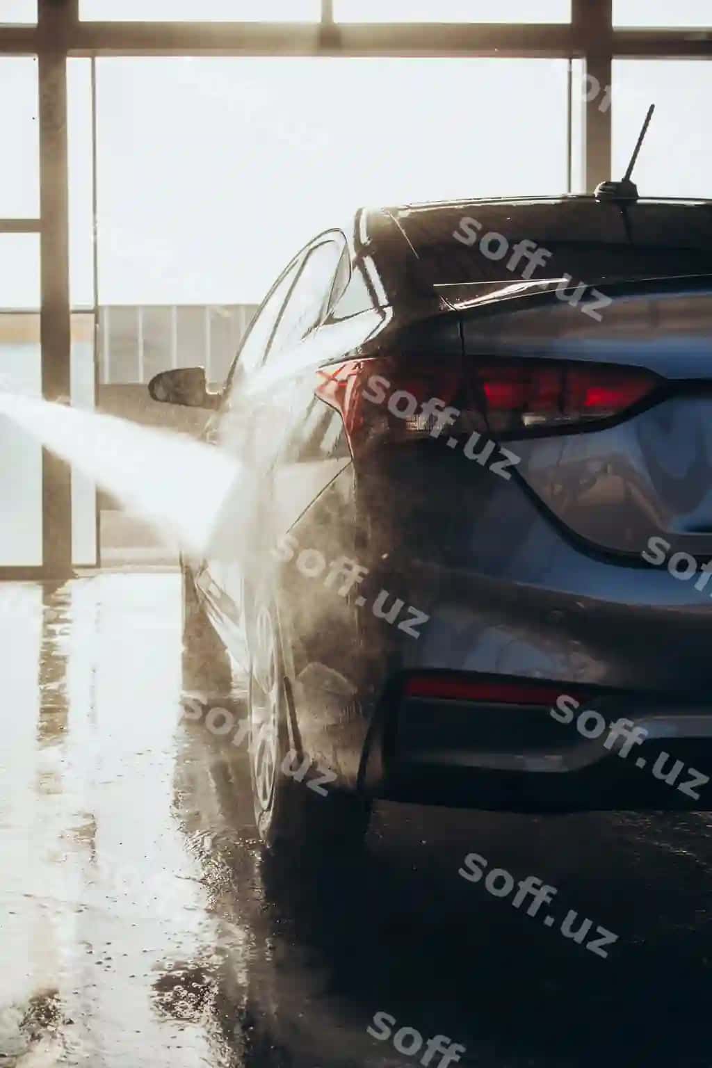 Er o'z avtomobilini o'z xizmat ko'rsatish avtomobil yuvishda shlangdan bosimli suvdan foydalangan holda yuvadi. | Man washes his car selfservice car wash using hose with pressurized water