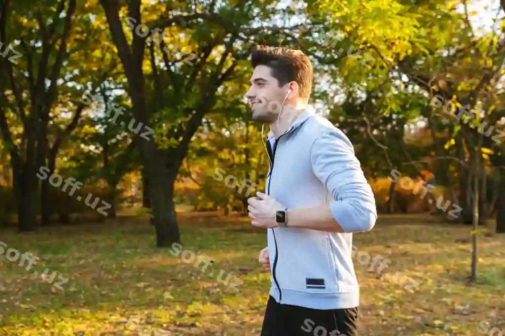Rasm chiroyli yosh sportchi tashqarida parkda musiqa eshitmoqda naushnik bilan yug'ilmoqda | Image handsome young sportsman outdoors park listening music with earphones running